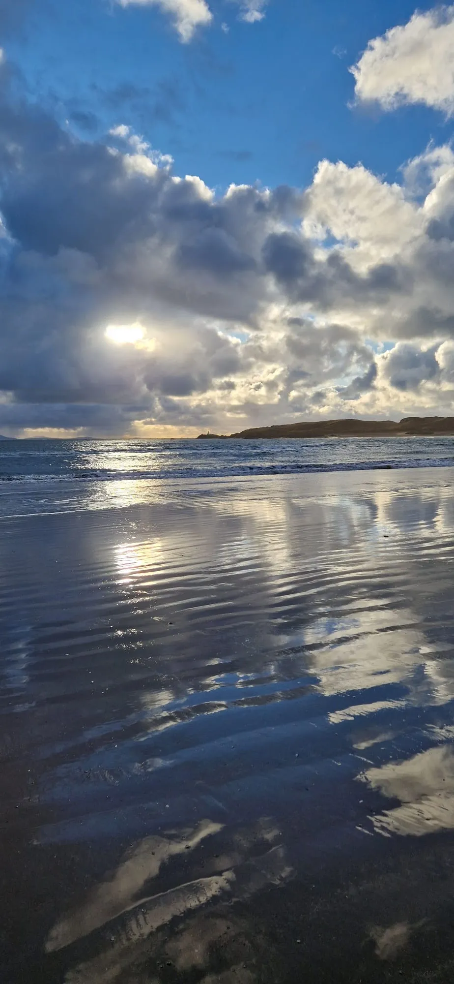 Low winter sun over Newborough beach, Anglesey, with cloud reflected in the wet sand and Ynys Llanddwyn on the horizon