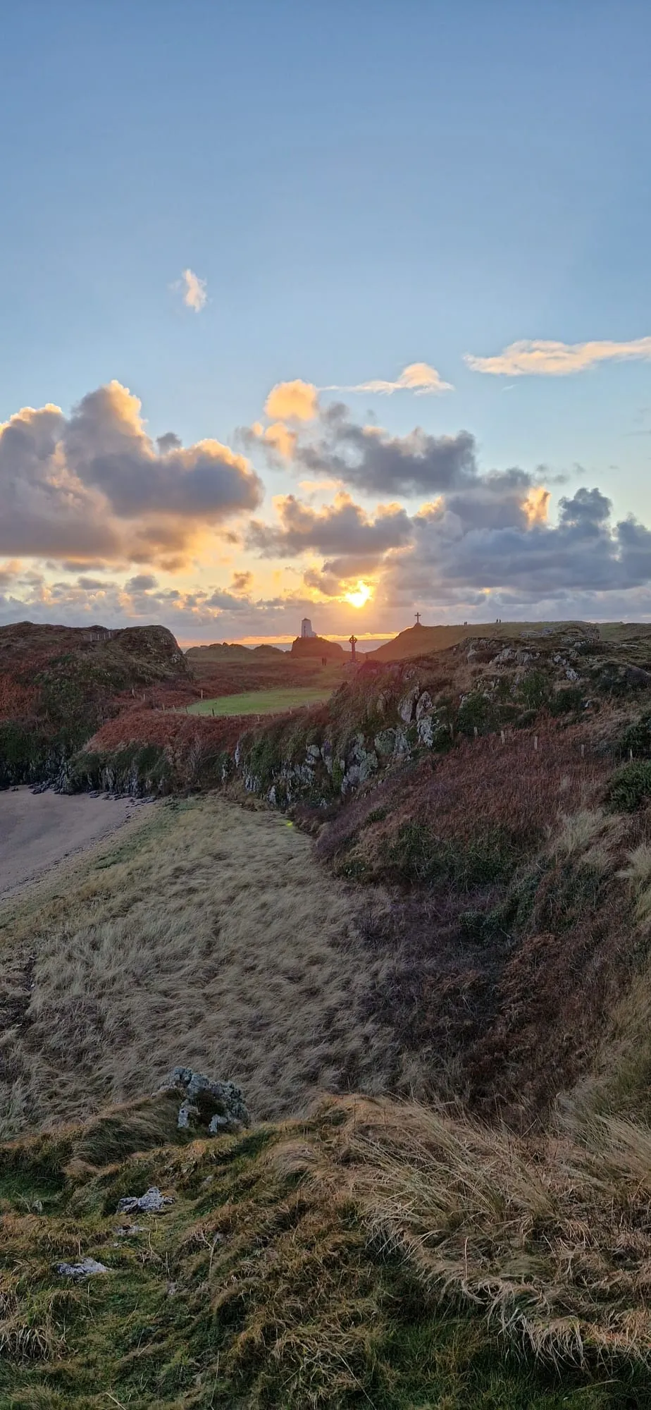 Golden late-afternoon light over Ynys Llanddwyn, Anglesey, with the crosses and lighthouse silhouetted on the ridge